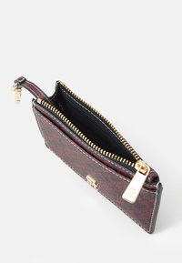 Zippered wallet in red and black patterned material with gold hardware. Interior shows black lining and a compartment for cards or coins.