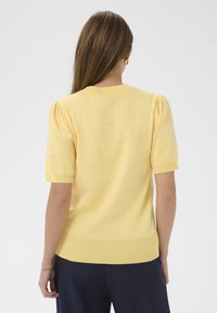 Gelber Strickpullover mit kurzen Puffärmeln, Rundhalsausschnitt und geripptem Saum. Der Stoff hat eine weiche, glatte Textur, ideal für legere Kleidung.