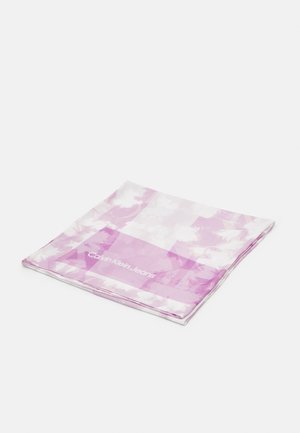 Foulard carré plié avec un motif floral rose et blanc et le texte "Calvin Klein Jeans" sur un fond uni.