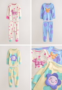 Deux ensembles de pyjamas pour enfants : crème avec des pois roses et une licorne, bleu avec des nuages violets et un lion ; jaune avec des nuages bleus et une fleur souriante.