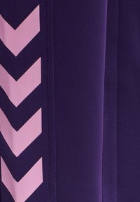 Nahaufnahme eines dunkelvioletten Stoffes mit einer vertikalen Reihe pinkfarbener, nach unten zeigender Chevronpfeile auf der linken Seite.