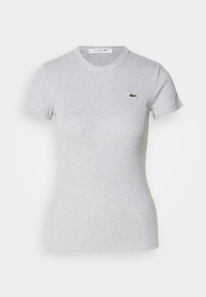 Világosszürke, testhez álló, rövid ujjú póló, kerek nyakkivágással, bal mellrészén egy kicsi zöld Lacoste krokodil logóval.