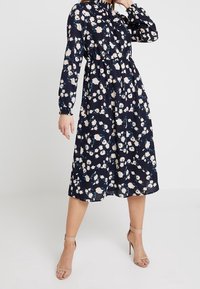 Navy västerhalmidi klänning med långa ärmar, samlad midja och ett helsprintat mönster av ljusrosa och teal blommor. Lättviktigt material.