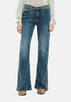 Jeans a zampa d'elefante in denim blu con vita media, design a cinque tasche e dettagli di cucitura visibile. La trama del tessuto è liscia e leggermente usurata.