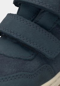 Baskets en daim bleu foncé avec des bandes Velcro, des coutures détaillées et une forme classique avec une finition texturée.