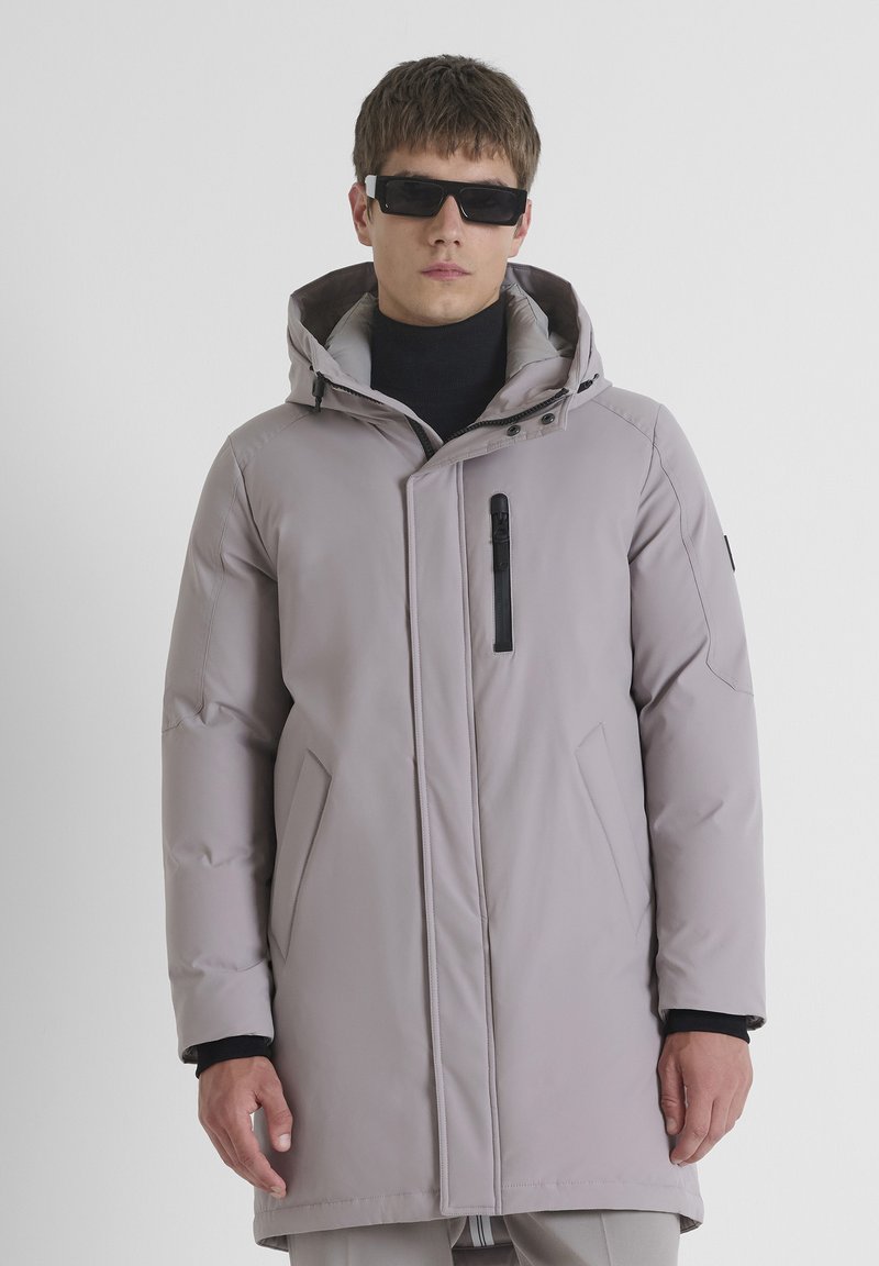 Lichtgrijze gewatteerde parka jas met een capuchon, rits- en drukknoopsluiting, schuine zijzakken en een zipped borstzak. Gladde textuur en modern ontwerp.