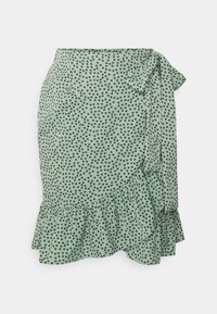 Falda envolvente verde menta con lunares negros, con dobladillo rizado y detalle de lazo lateral. Fabricada en una tela ligera con una textura suave.