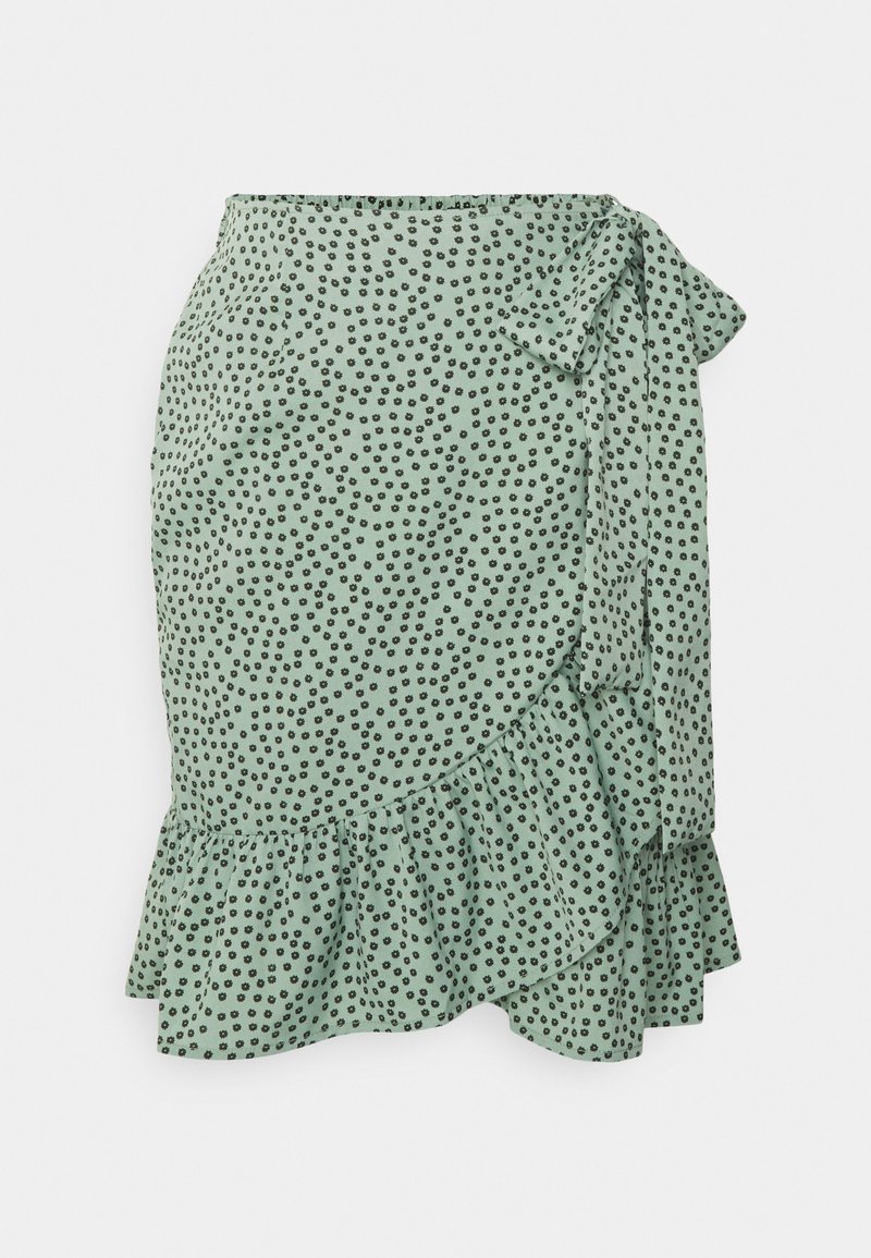 Falda envolvente verde menta con lunares negros, con dobladillo rizado y detalle de lazo lateral. Fabricada en una tela ligera con una textura suave.