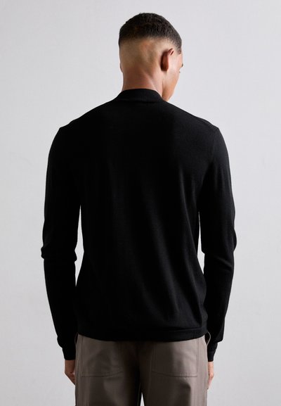 Schwarzer Strickpullover mit langen Ärmeln, Rundhalsausschnitt und taillierter Silhouette. Weicher Stoff und minimalistisches Design zeichnen ihn aus.