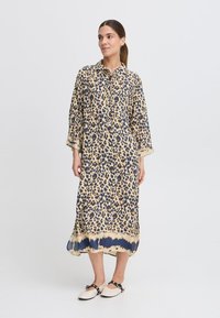 Langarmkleid mit Leopardenmuster, Kragen, Dreiviertelärmeln und einem fließenden Saum, der von Beige zu Marineblau am unteren Ende übergeht.