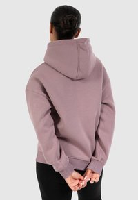 Haut à capuche surdimensionné en mauve clair, fabriqué en tissu doux, doté d'une poche kangourou, de poignets côtelés et d'une grande capuche.