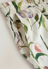 Záber na látku s elastickým pásom a kvetinovým vzorom, zobrazujúci detail bočného vrecka.