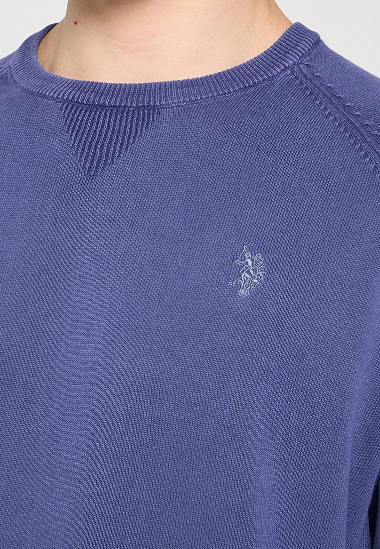 Niebieski sweter dzianinowy z prążkowanym okrągłym dekoltem, z subtelnym haftowanym logo na piersi oraz teksturowymi detalami wzdłuż szwów.