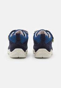 Navy blue athletic shoes with suede and mesh materials, featuring a textured white sole, adjustable strap, and contrasting green accent on the heel.