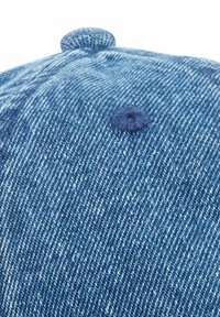 Denimkasket med en falmet blå farve, med en rund knapdetalje på toppen. Teksturen viser let variation og syninger.