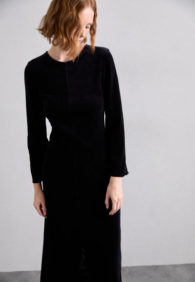 Black velvet long-sleeve dress with a round neckline and a straight silhouette, featuring a front seam and subtle texture.