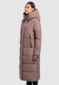 Abrigo largo acolchado en malva con una gran capucha, bolsillos laterales con cremallera y secciones acolchadas. Presenta una textura exterior lisa y suave.