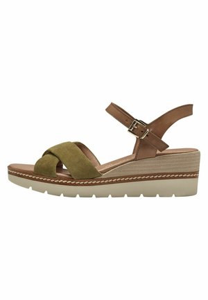 Sandale compensée avec une bride en cuir marron et un passants en suède vert. Elle présente une épaisse plateforme beige à la finition texturée. Sangle à boucle incluse.
