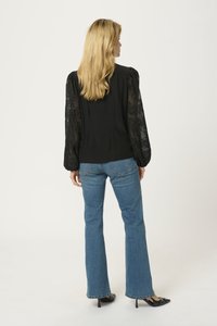 Black blouse with lace balloon sleeves, paired with blue flared jeans. The blouse features a tailored fit and gathered detailing at shoulders.