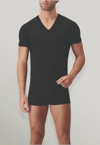 T-shirt nera a maniche corte con scollo a V, realizzata in tessuto morbido, aderente, con una texture liscia e materiale elasticizzato per il comfort.