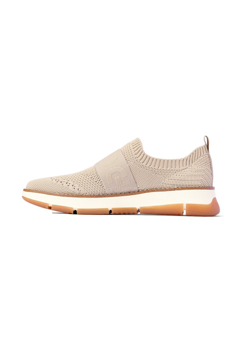 Beige gestrickte Slip-On Sneaker mit elastischem Streifen, weißer Zwischensohle und segmentierter Gummisohle in Beige, seitliche Ansicht vor weißem Hintergrund.