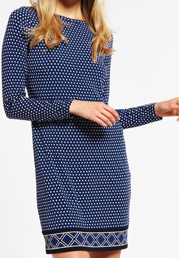 Robe à manches longues bleu marine avec un motif à pois, coupe ajustée et bordure géométrique noire à l'ourlet. Texture lisse et longueur mi-cuisse.