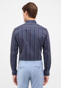Camicia a maniche lunghe con righe verticali blu navy, azzurro chiaro e bordeaux. Collo con bottoni alle polsi, design aderente e texture del tessuto liscia.