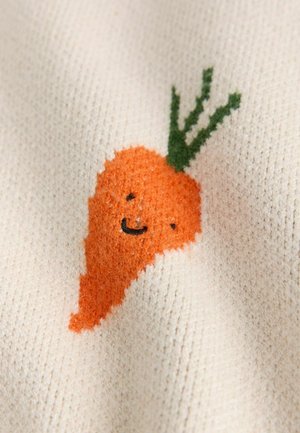 Kötött anyag, amelyen egy narancssárga sárgarépa látható, mosolygós arccal és zöld levelekkel, krémszínű, mintázott háttéren.