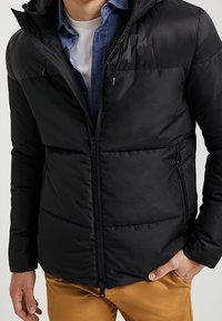 Black puffer jacket with stitched panels, zippered pockets, and a hood. Features a sleek, matte finish and a zip closure.