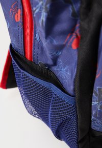 Backpack with a blue and black design, featuring red zippers, spider graphics, and a mesh pocket. Durable fabric with distinct textures.