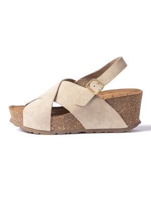 Beige suede wedge sandal with cork platform sole, crisscross straps, and adjustable ankle strap with gold buckle on white background.