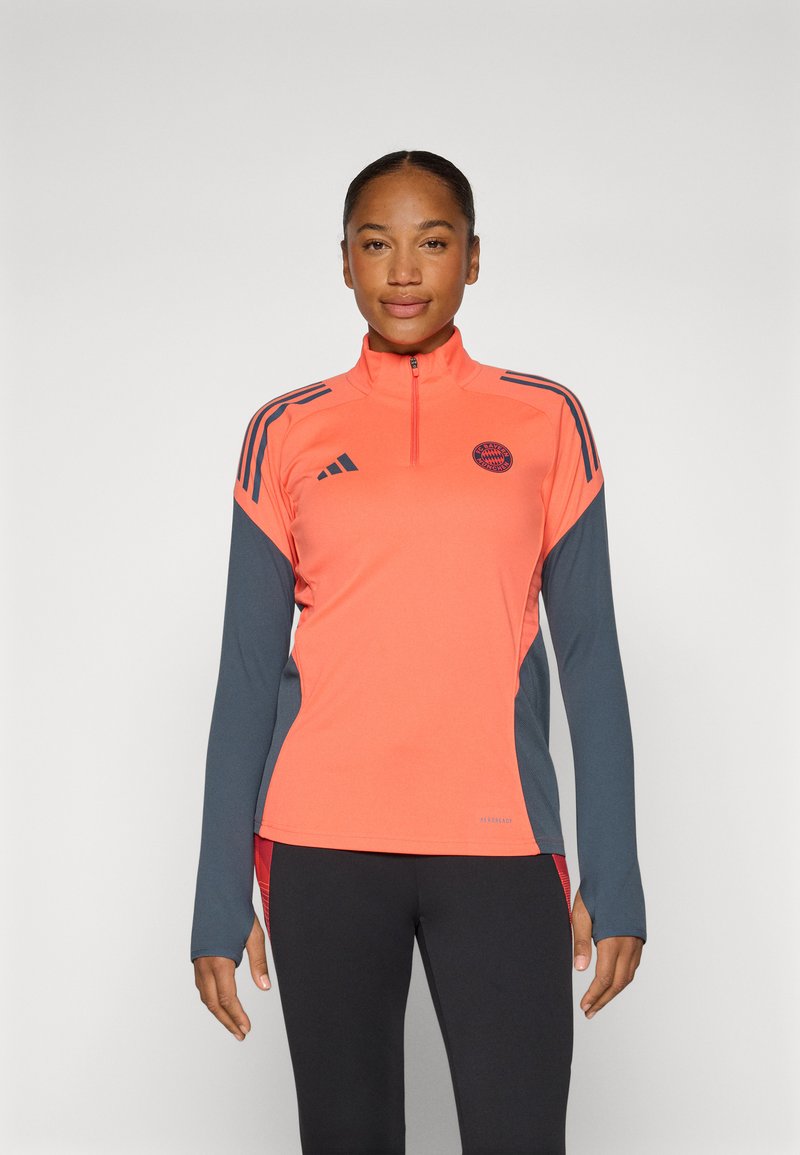 Long-sleeve athletic top in bright coral with gray accents. Features a half-zip collar and three horizontal stripes on shoulders.