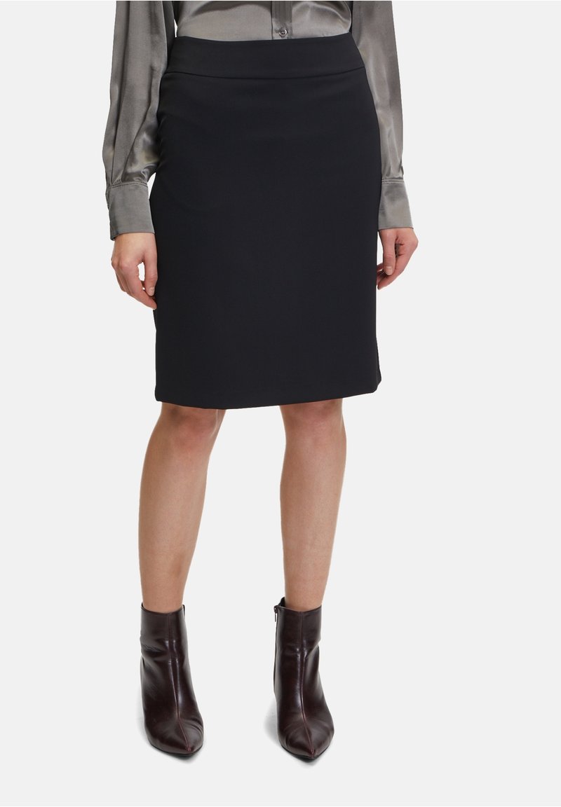 Svart figurnära kjol i slät tyg med hög midja. Kombinerad med en grå långärmad skjorta och burgundyröda ankelstövlar.