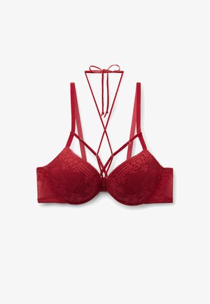 Soutien-gorge en dentelle rouge avec bonnets rembourrés, bretelles ajustables et détail décoratif entrecroisé avec un nœud au niveau du décolleté.