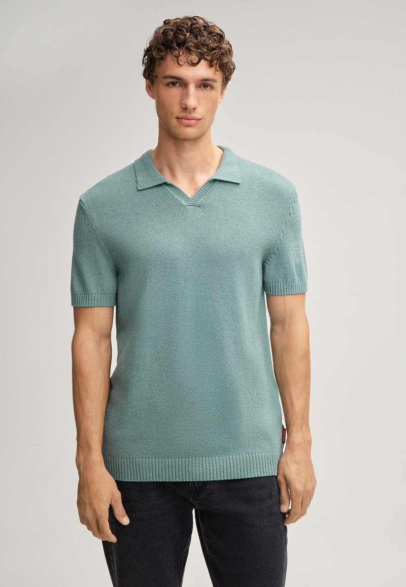 Polo a maniche corte in maglia di un verde teal chiaro con scollatura a V e costine ai polsini e all'orlo. Tessuto liscio e vestibilità casual.