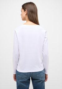 Weißes Langarmoberteil mit rundem Ausschnitt, aus einem glatten Baumwollmix hergestellt, mit lockerem Sitz und einfachem Design.