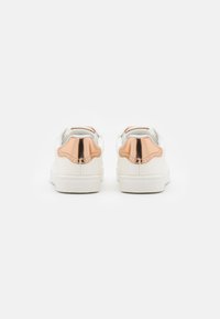 Hvite joggesko med en glatt læroverdel, som har speilreflekterende rose-gull detaljer på hælen og en teksturert såle. Minimalistisk design.
