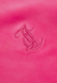 Rožinė zomšos medžiaga su įspaustu monogramų logotipu šviesesnėje rožinėje spalvoje, demonstruojanti švelnų tekstūrą ir lygią išvaizdą.