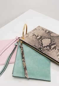 Tre borsette: una pochette in pelle rosa, una borsa in suede verde e una grande borsa con stampa pitone, dotata di un manico ad anello dorato e dettagli con zip.