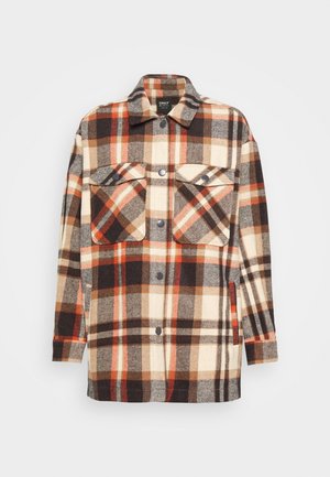 Płaszcz z długim rękawem zapinany na guziki, w brązowo-beżowo-pomarańczową kratę, z klapanymi kieszeniami na piersi i kołnierzem na jednolitym tle.