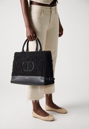 Black textured handbag with a plush exterior, leather base, and double round handles. Features visible branding, leather accents, and a structured shape.
