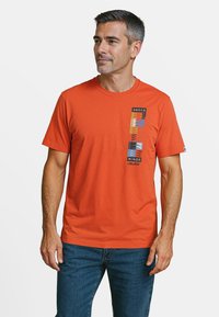 Oranje katoenen T-shirt met een grafische print met strepen en blokkleuren aan de linkerkant. Ronde hals en korte mouwen.