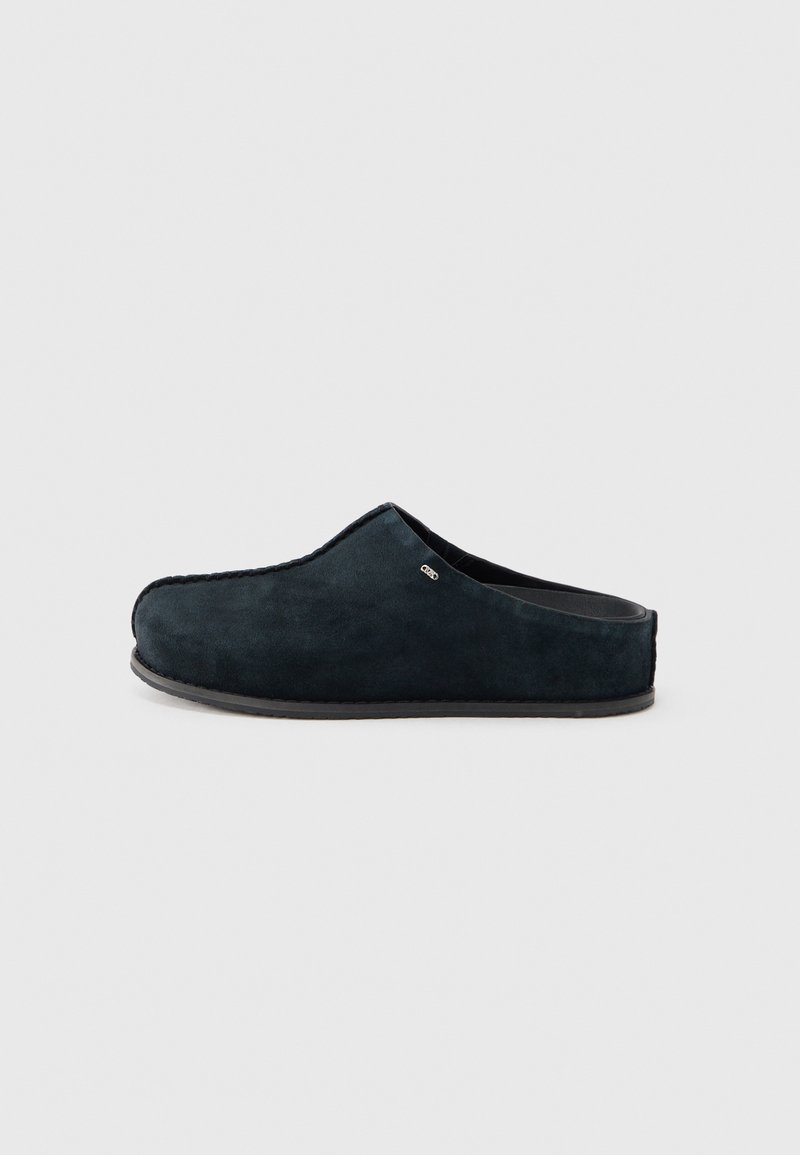 Black suede slip-on slipper with low heel and rounded toe, shown from the side on a white background.
