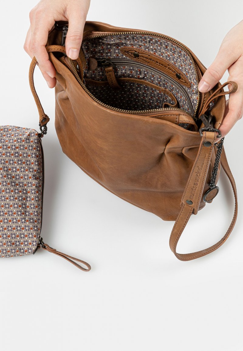 Borsa a tracolla in pelle marrone con finitura strutturata e chiusura a zip. L'interno presenta una fodera a motivo. Include una piccola pochette con motivo.
