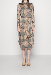 Mönstrad skjortklänning i mjukt tyg, med en blandning av pastellfärger, knäppning fram, långa ärmar och midjeband. Mönstren inkluderar kedjor och rutnät.