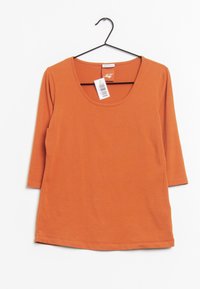 Rostorange, t-shirt med 3/4 ärmar i mjukt tyg, har en bred halsringning, rak fåll och en skötselvetenskap på baksidan av nacken.