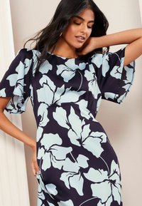 Abito floreale di colore blu navy con motivo di grandi fiori azzurri, caratterizzato da maniche a campana corte e scollo rotondo. Tessuto dalla texture liscia.