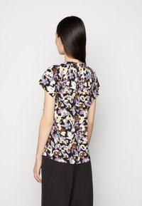 Blusa floral com mangas curtas, apresentando um fundo preto e padrões de flores multicoloridas em roxo, branco, amarelo e castanho.