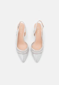 Silvriga högklackade skor med spetsig tå, med en glittrande ovandel och genomskinliga remmar, samt en nude-färgad innersula med varumärkeslogga.