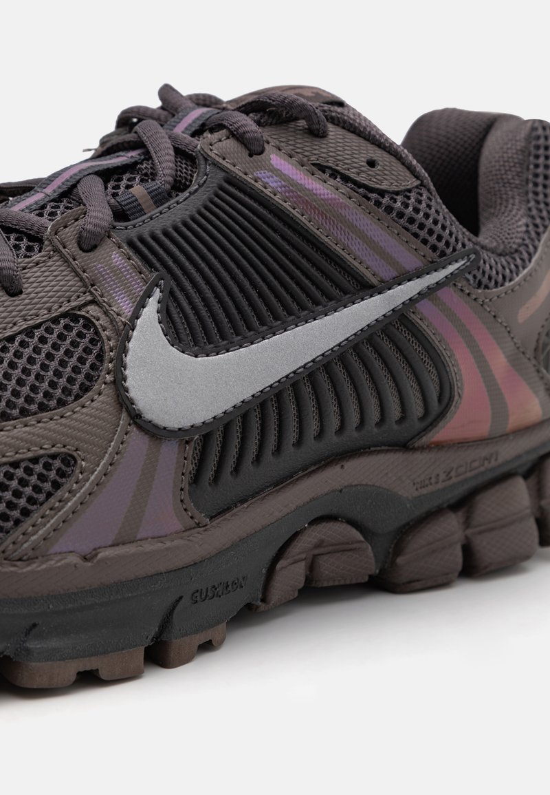 Nike hardloopschoen met een donkergrijze bovenkant met mesh-panelen, reflecterende zilveren swoosh, gestructureerde accenten en een gevoerde, geg segmenteerde buitenzool.